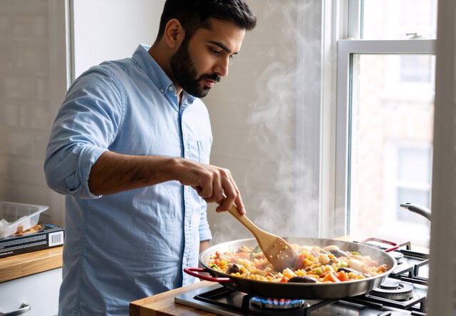 Man cooking food in a home kitchen producing cooking vapors and VOCs