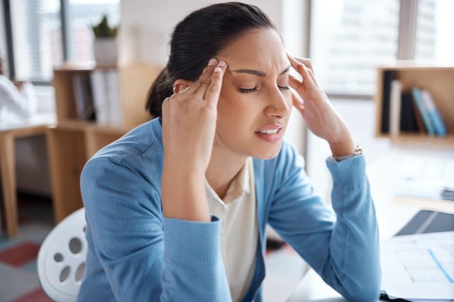 Woman experiencing headache and discomfort potentially related to poor indoor air quality and VOC exposure
