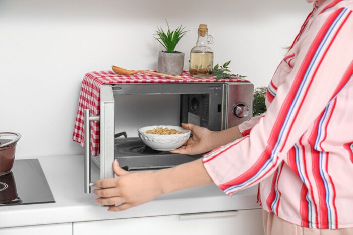Employees using a microwave in an office pantry while food odors spread into the workspace